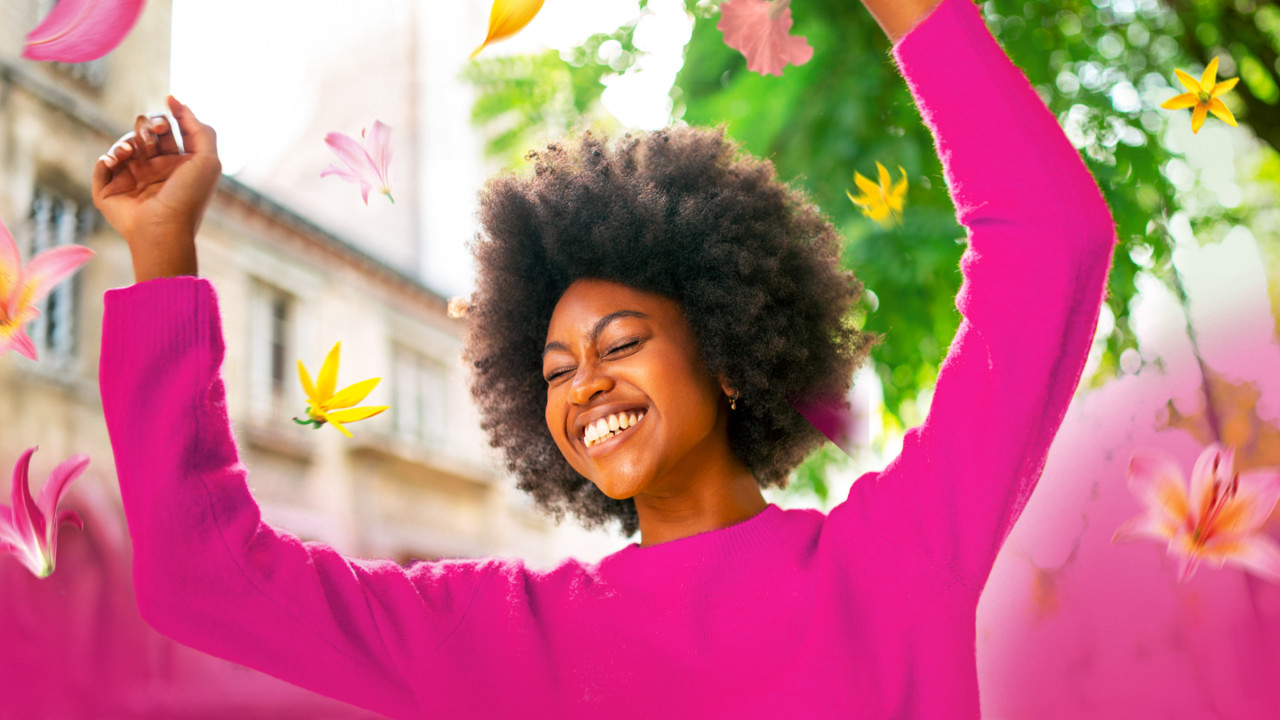 Woman in pink jumper, dancing and surrounded by flowers